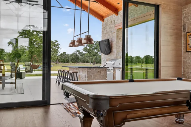Covered entertainment area with pool table and outdoor kitchen