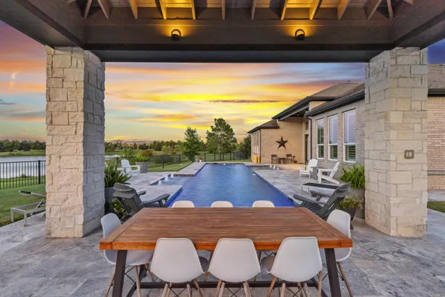 Covered outdoor dining area overlooking pool at sunset