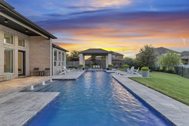 Backyard pool and patio beneath a sunset sky