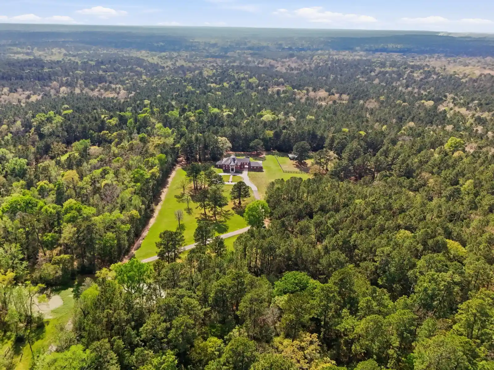 Home and approach surrounded by trees and open land
