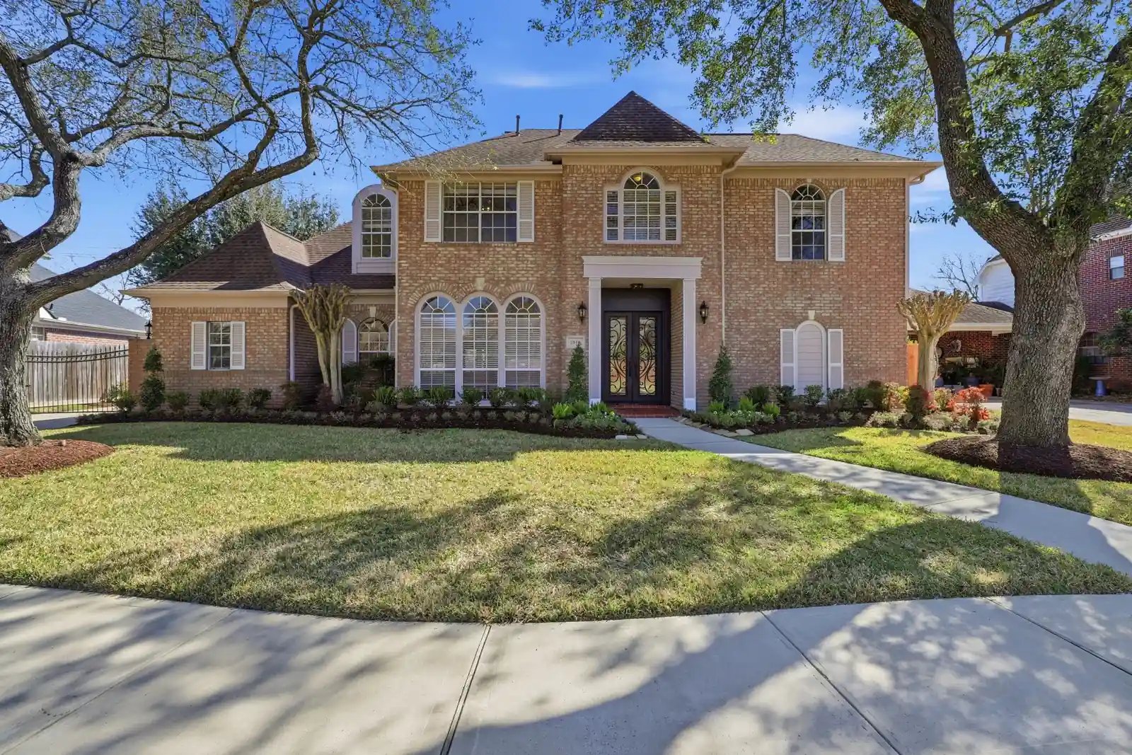 Two-storey brick home with columned entrance and mature trees